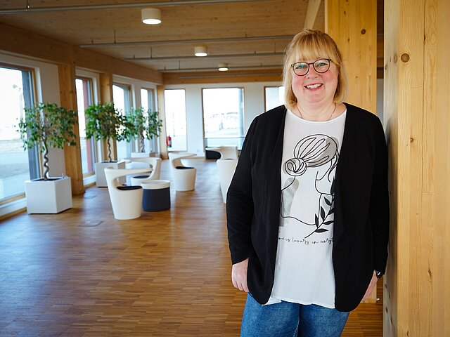 Silke steht an einen Balken gelehnt im JUWI Gebäude in Wörrstadt.